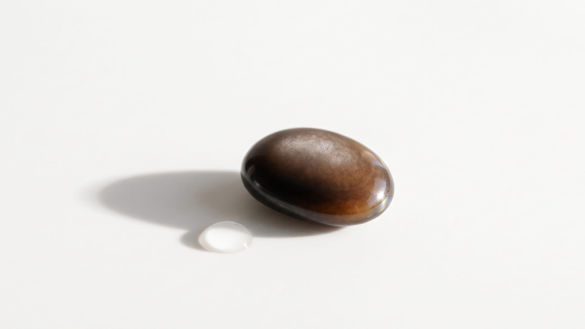 아침 창가의 흰 바탕 위, 길들여진 브라운-블랙 조약돌과 물방울 하나